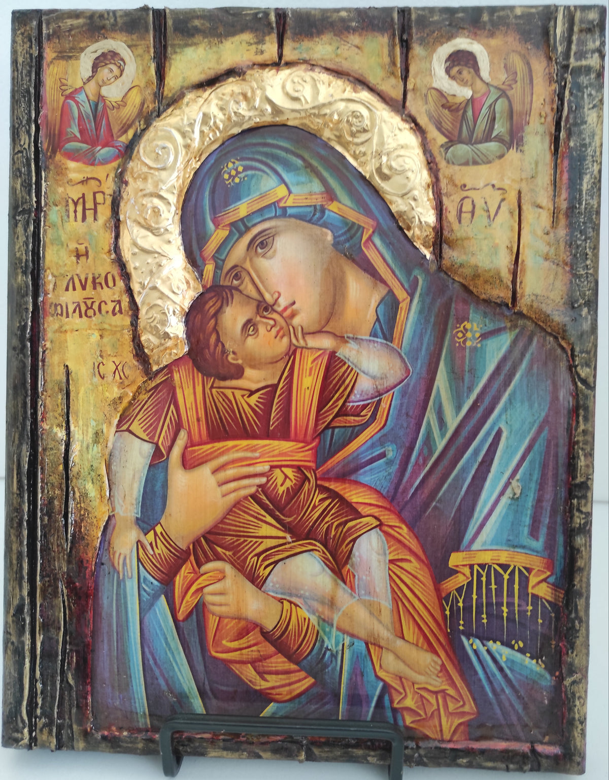 An antique-style religious icon design on a wooden panel, depicting the Holy Family with a gold-leaf halo and a dark metal latch on the right side, photographed against a plain white background.
