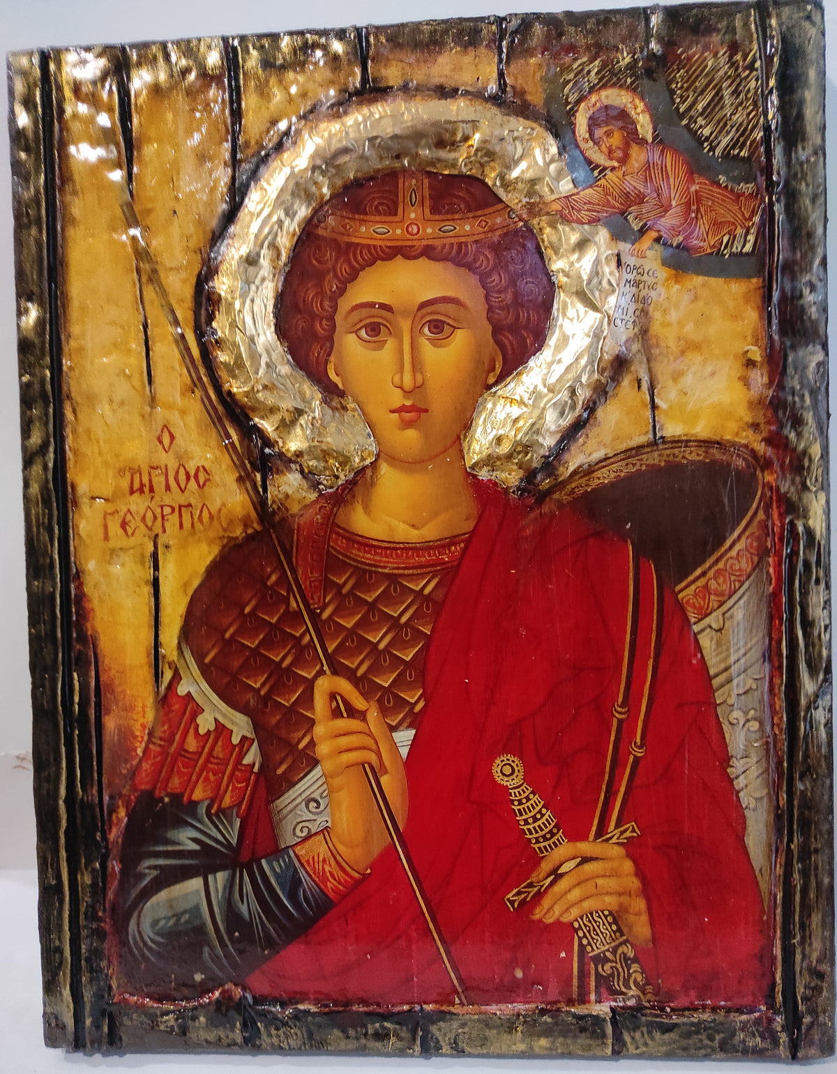 A traditional Russian Orthodox icon of Saint George on a wooden panel with gilded leaf detailing, featuring a red robe, gold halos, and a dark background.