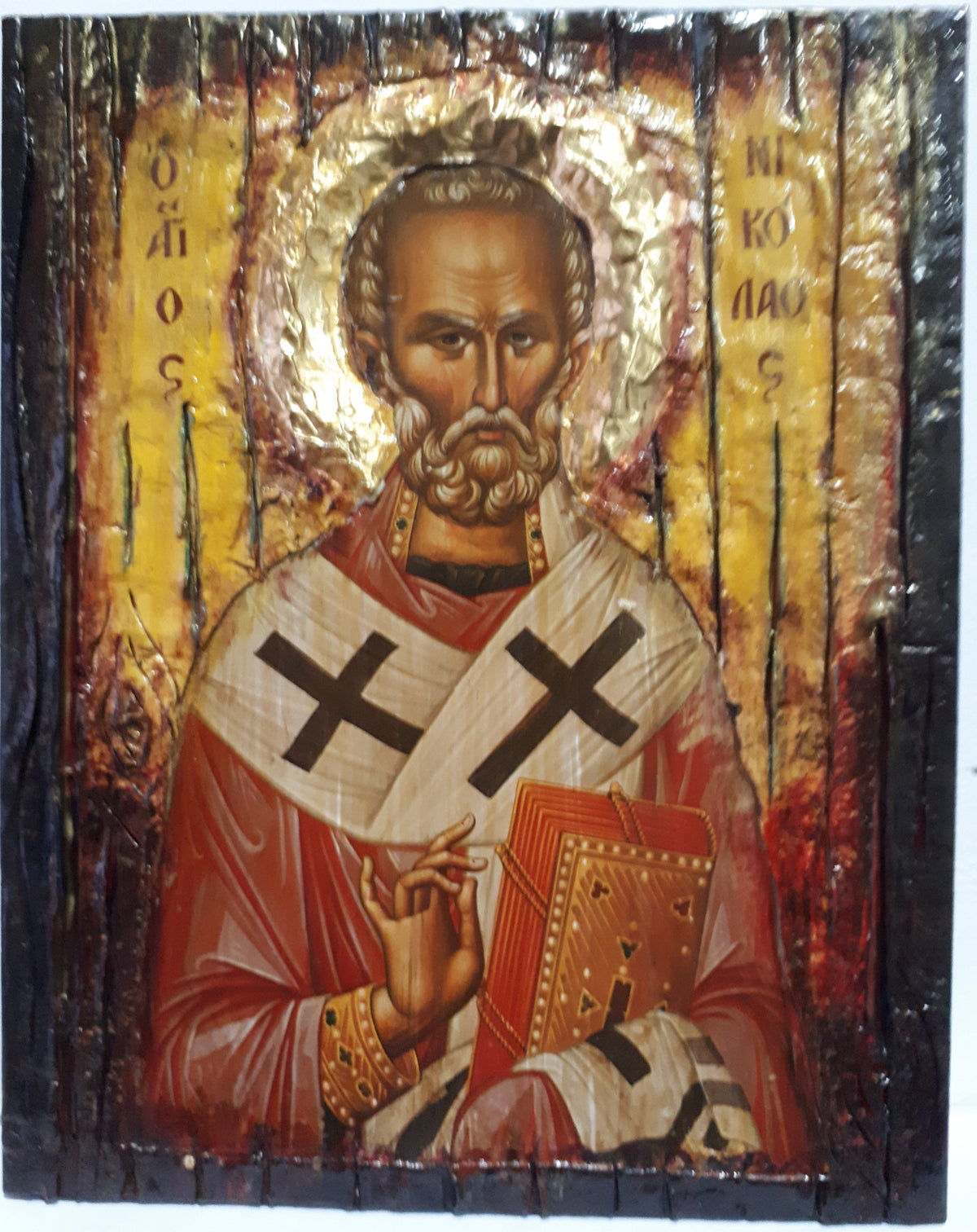 A rustic wooden religious icon design of Saint Nicholas, featuring a gold halo, red and white robes with black crosses, and Cyrillic inscriptions on a distressed dark wood background.