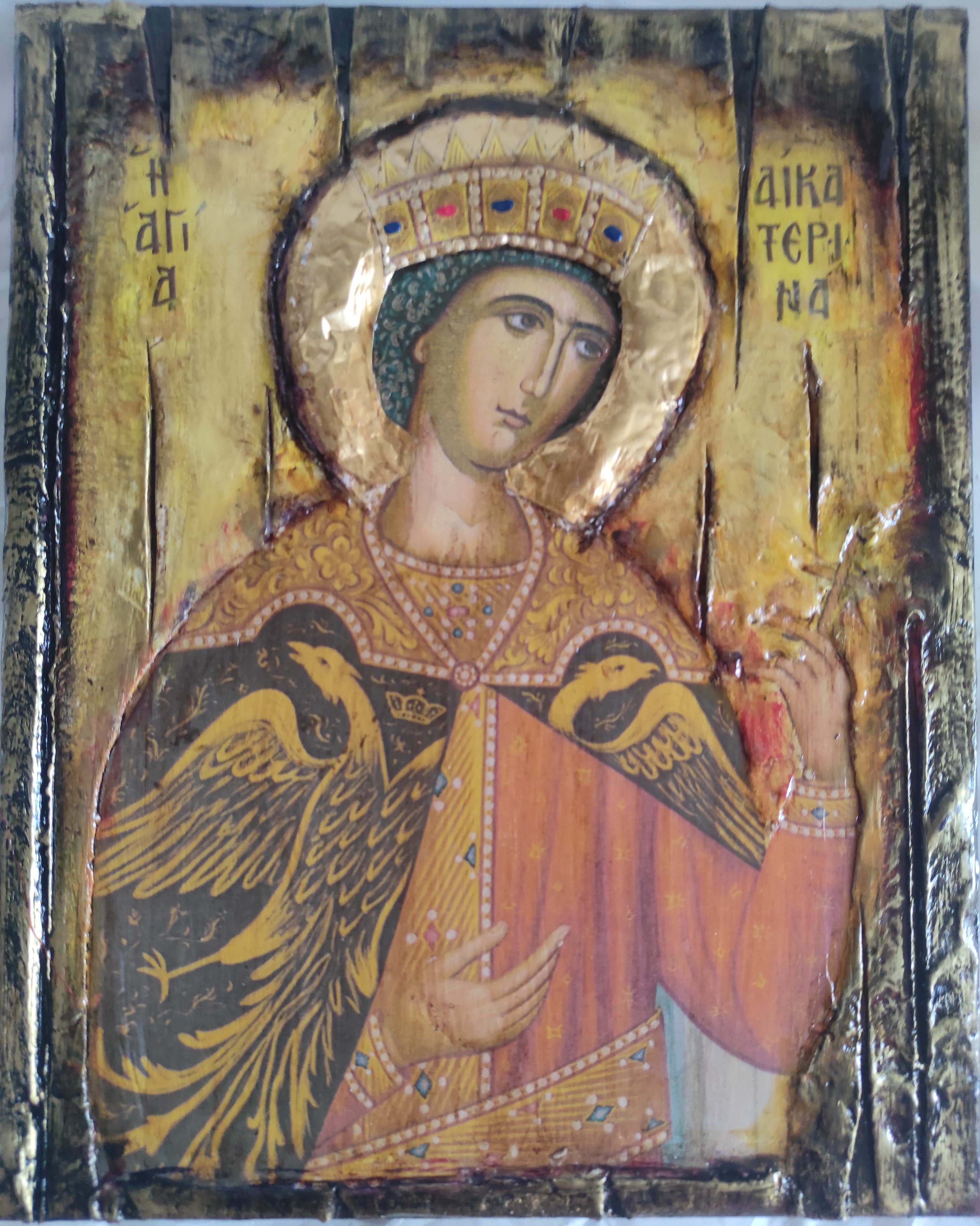 An antique Byzantine-style religious icon painting of a crowned female saint or angel with gold leaf, black wings, and red robes, photographed against a white background.