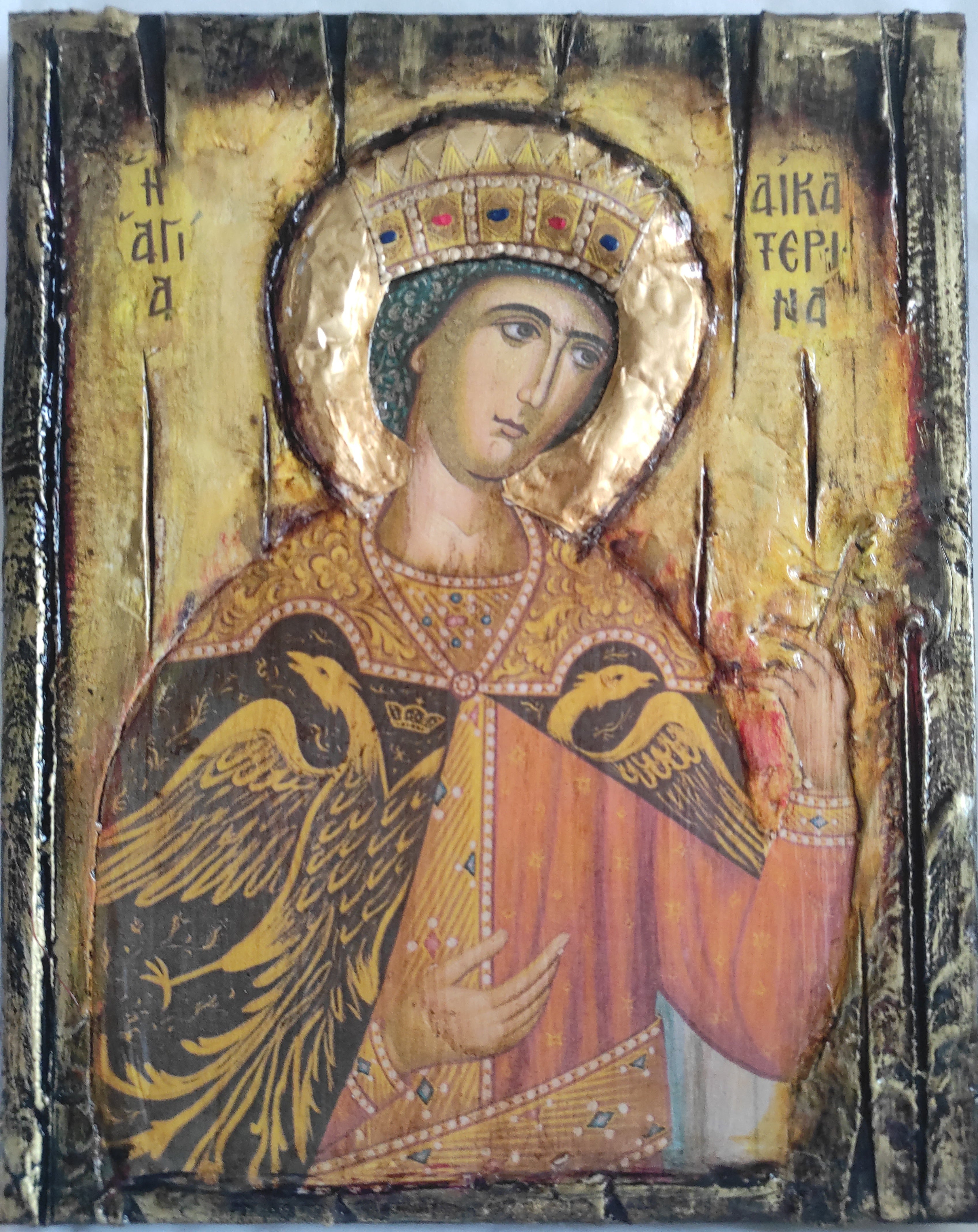 An antique religious icon  on a wooden panel depicting a haloed saint in gold and red robes, with two black birds and Greek lettering, photographed flat against a light background.
