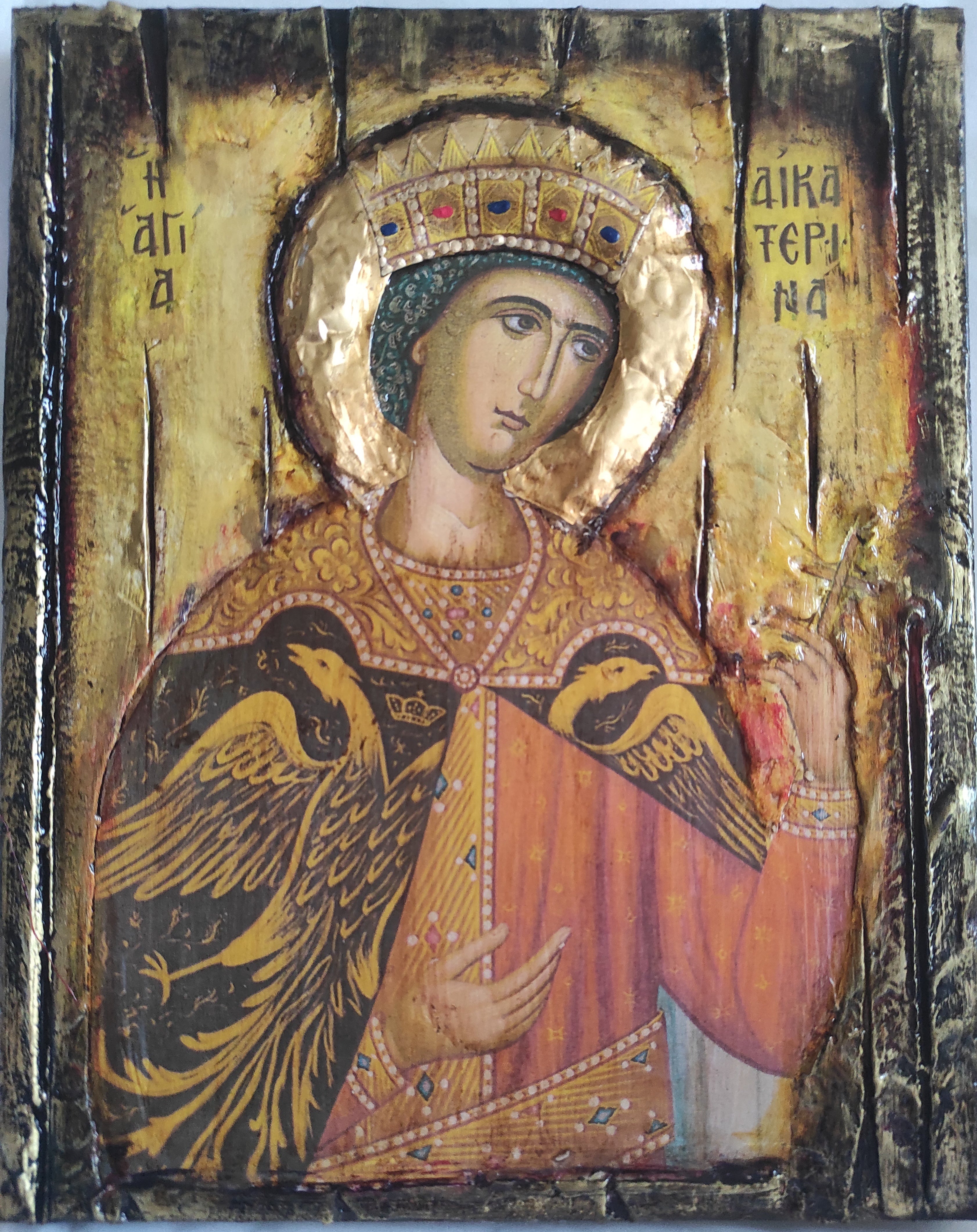 An antique religious icon of Saint George on a textured gold leaf background, featuring a dark wood border and a large black bird.