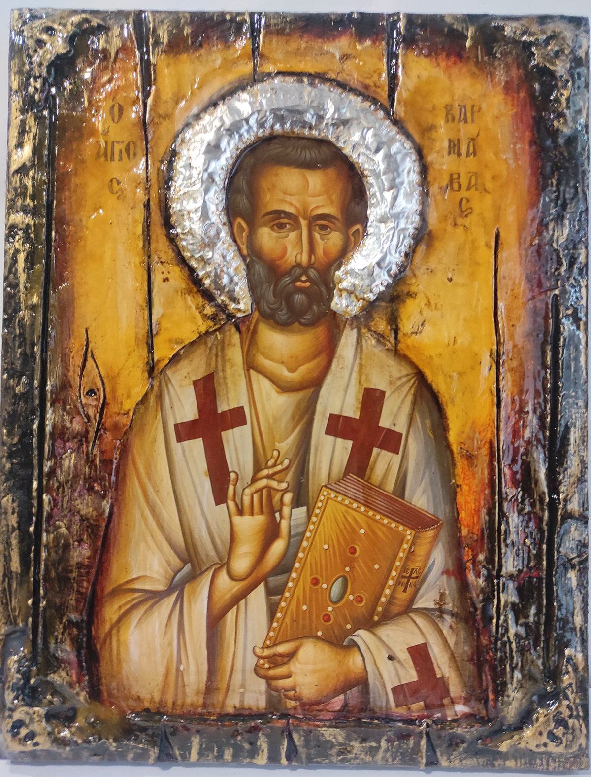 An antique-style religious icon design of Saint Barnavas on a distressed wooden panel background, featuring a gold background, a silver foil halo, and red crosses on the robes.
