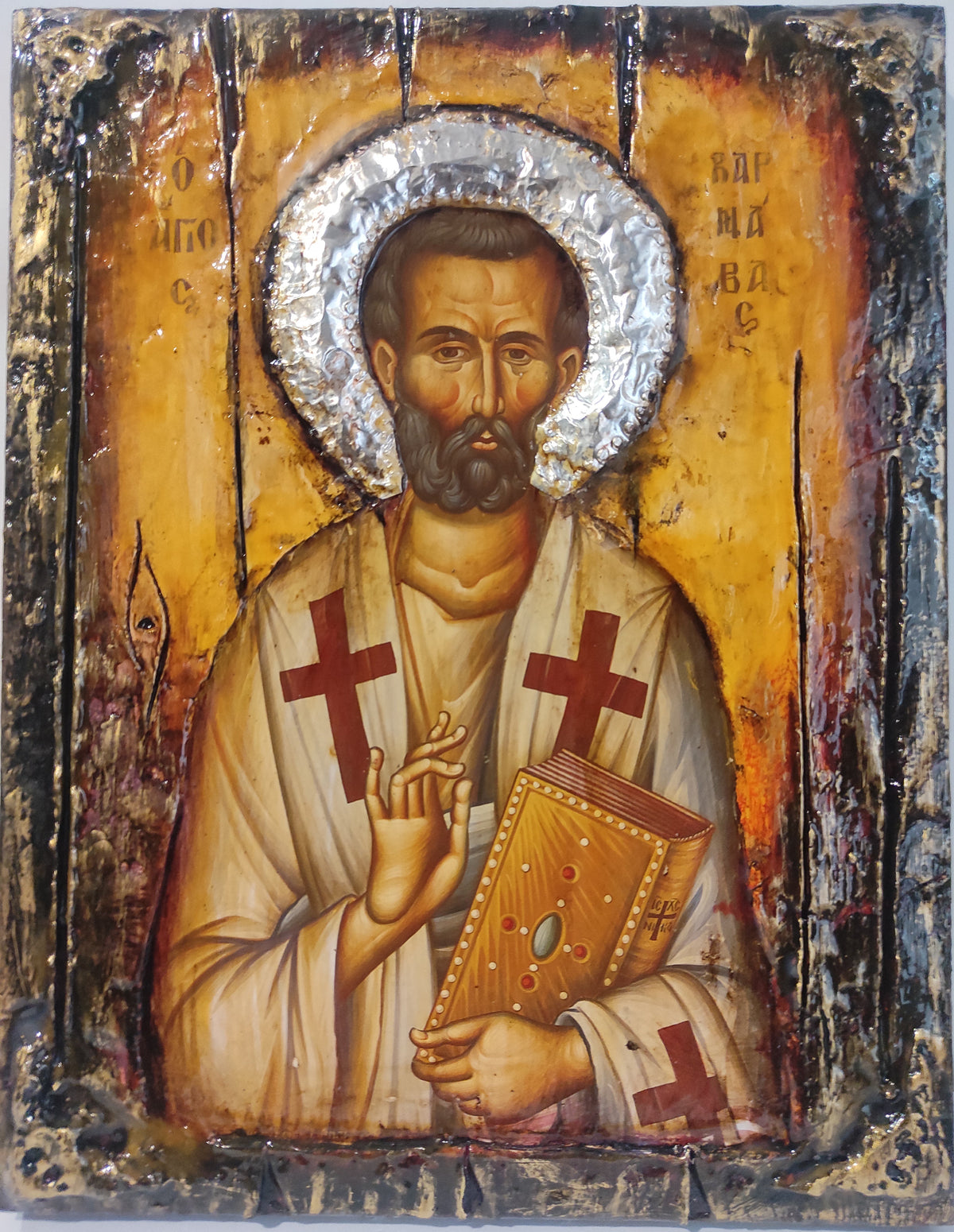 An antique religious icon design of Saint Barnavas on a distressed wooden panel with a metallic silver halo and a yellow-gold background.