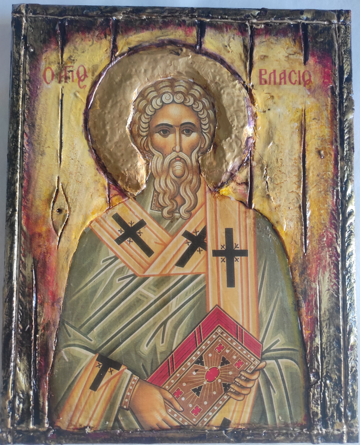 An antique-style religious icon design of Saint Vlasios, featuring a textured gold background, a halo, and a figure in green and orange robes holding a book, with Cyrillic inscriptions at the top.