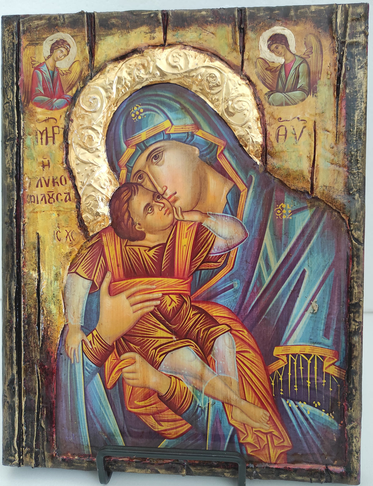 An antique wooden Russian Orthodox icon depicting the Holy Family, featuring a distressed gold background, blue and orange robes, and a dark metal latch on the right side.