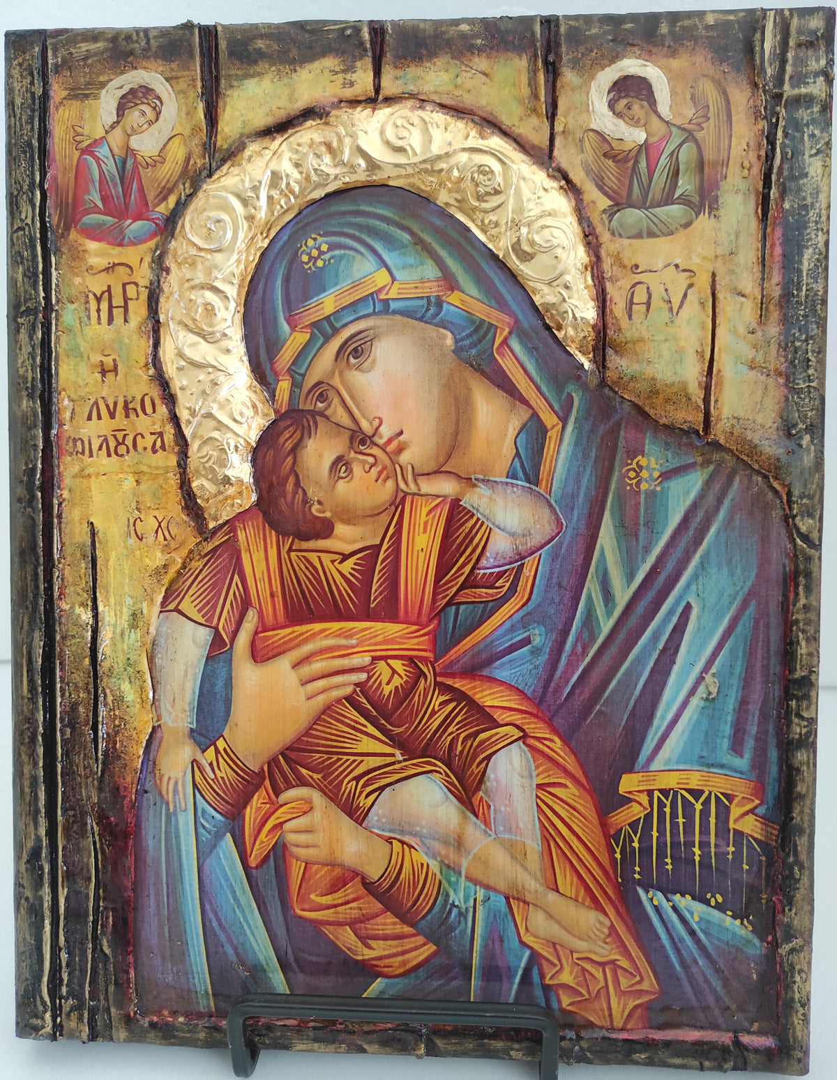 An antique-style wooden religious icon design depicting the Holy Family, featuring a gold-leaf halo, blue garments, and warm brown tones, mounted on a white background.